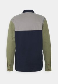 Camicia di cotone con un design a blocchi di colore: parte superiore grigia, parte centrale blu navy e maniche verde oliva. Presenta polsini con bottoni e colletto a punta.