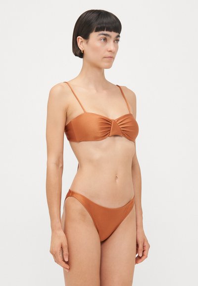 Pruun bikinit komplekt, mis koosneb bandeau-topsis pleedi esiosa ja õhukeste rihmadega, ning madala vöökohaga bikiinipükstest, kõik satiinviimistluses.
