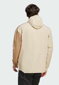 Beige en bruin color-block jas met capuchon, met een gladde textuur en lange mouwen. Naaidetails op schouders en zijkanten.