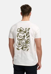 Hvid bomulds t-shirt med et grønt blomster graphic design på ryggen, med varierede blomstermønstre og blade, korte ærmer og rund hals.