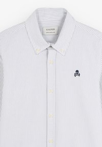Camisa de botones a rayas en gris claro y blanco. Tela suave con un cuello clásico, que presenta un pequeño logo de una calavera azul oscura en el pecho.