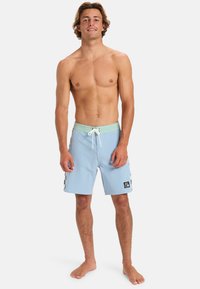 Světlomodré plavky s mentolově zeleným pasem a šňůrkou, s kostkovanými akcenty a logem na boku.