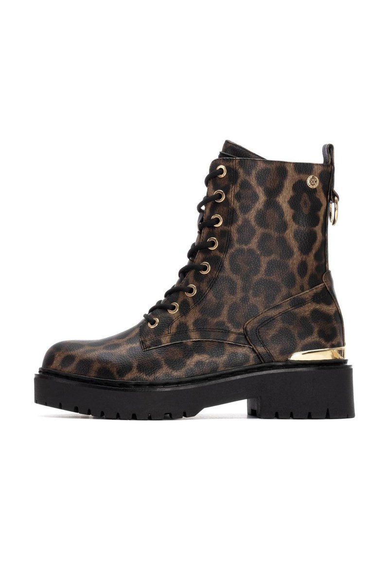 Botas de tobillo de estampado de leopardo hechas de cuero con herrajes dorados, cordones en la parte delantera, suela gruesa negra y detalles con cremallera en el lateral.