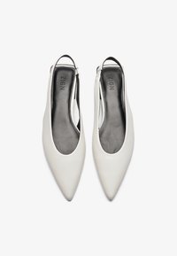 Valkoiset kärjelliset slingback-kengät, joissa on sileä nahkapinta ja harmaa sisäpohja. Ominaisuuksina ohut musta hihna, joka takaa varman istuvuuden.