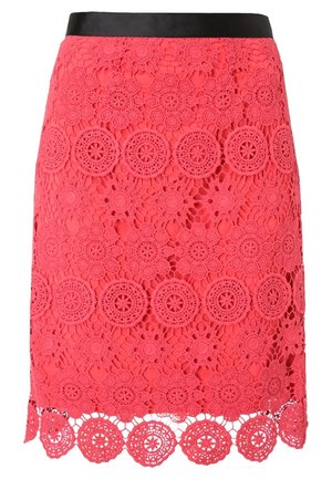 Jupe en dentelle rouge avec des motifs floraux et circulaires en crochet, présentant une ceinture noire et un ourlet festonné.
