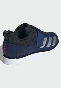 Tmavě modrá sportovní obuv s texturovaným textilním svrškem, suchým zipem, šedými akcenty a bílou podrážkou. Logo "POWERLIFT" na patě.