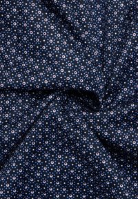 Marineblauer Stoff mit einem kleinen geometrischen Muster in Hellblau und Weiß, das florale Motive und Formen in einem Raster-Layout zeigt.