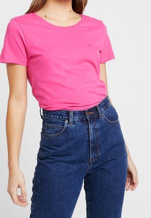 Pink cotton t-shirt with a round neckline and short sleeves, paired with high-waisted, dark blue denim jeans featuring a classic fit.