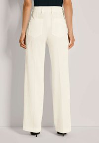 Weite, gerippte Hosen in Off-White mit hoher Taille, ausgestattet mit zwei hinteren Taschen und einer glatten Textur. Der Saum endet über dem Knöchel.
