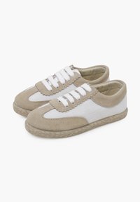 Scarpe in tela beige e bianche con accenti in suede, bordi ondulati, lacci bianchi e suola in corda di juta, che mostrano un design informale.