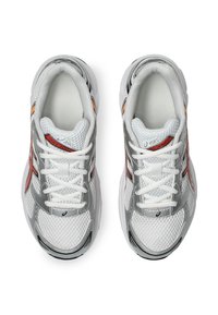 Harmaat urheilukengät, joissa on verkkomateriaali, valkoiset nauhat, oranssia ja punaista korostavaa väriä, pehmustettu pohja ja erottuva teksturoitu päällyste.