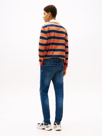 Camisa de manga larga a rayas en naranja, azul marino y blanco; vaqueros azules; zapatillas blancas y azul marino; corte relajado; costuras visibles y bolsillos traseros.