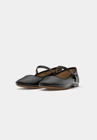 Ballerine in vernice nera con punta appuntita, cinturino regolabile e suola piatta. Presentano una piccola fibbia metallica sul lato.