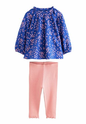 Haut long à manches fleuris bleus avec encolure froncée, associé à des leggings roses à côtes avec ourlets festonnés.