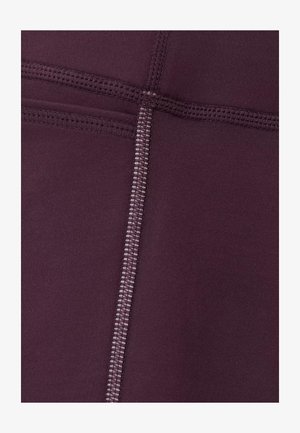 Bordeauxrode sportlegging met een gladde stof, platte naden en een gestructureerd stikselpatroon. Het ontwerp bevat subtiele contrasterende stikselaccenten.