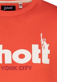 Camiseta de algodón roja con un gran texto blanco que dice "Schott" y "NUEVA YORK", con un gráfico de la Estatua de la Libertad en blanco.