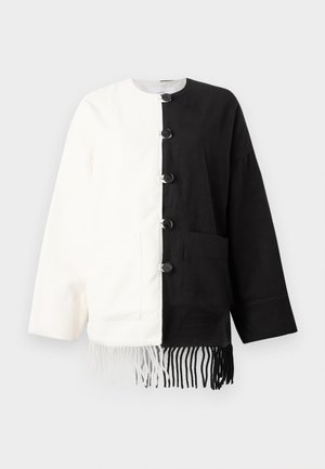 Long-sleeve jacket split vertically, left half white and right half black, with black buttons and matching fringe at the bottom.