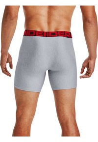 Boxers gris ajustés avec une ceinture élastique rouge portant l'inscription "UNDER" en lettres noires. Texture douce avec une finition lisse.