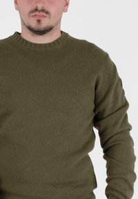 Oliwkowa, prążkowana dzianinowa sweter z okrągłym dekoltem i długimi rękawami. Posiada strukturalny materiał o dopasowanym kroju.