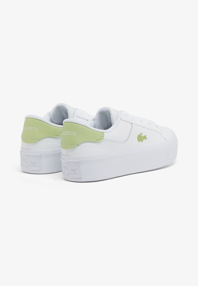 White Lacoste sneakers with light green heel tabs and logo, thick textured soles, and low-top design, shown from rear side angle.