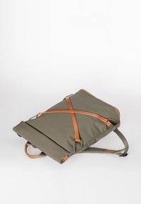 Zaino oliva con chiusura a rotolo, dotato di cinghie e manico in pelle marrone chiaro, posato disteso mostrando il dettaglio della cinghia laterale e della tracolla.