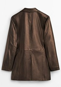 Veste longue en cuir marron à manches longues avec une couture droite dans le dos et une fente centrale, posée à plat sur un fond blanc.