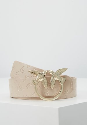 Beżowy pasek z tłoczonej skóry z złotą klamrą przedstawiającą dwa zwrócone do siebie ptaki siedzące na okrągłym pierścieniu, prezentowany na białej powierzchni.