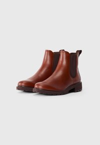 Bottes Chelsea en cuir marron avec des panneaux élastiques sur les côtés, bout arrondi et semelle en caoutchouc épaisse, présentant un design minimaliste.