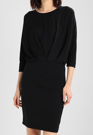 Schwarzes Kleid mit lockerem, drapiertem Oberteil und figurbetontem Rock. Es hat dreiviertellange Ärmel und einen glatten, elastischen Stoff.