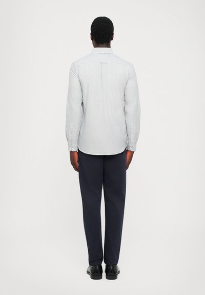 Camicia a maniche lunghe a righe bianche e blu, vista posteriore; colletto classico, tessuto liscio e design aderente abbinato a pantaloni blu scuro.