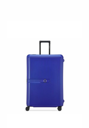 Maleta rígida azul con estrías verticales, asa negra telescópica, cuatro ruedas y una correa horizontal con detalle circular.