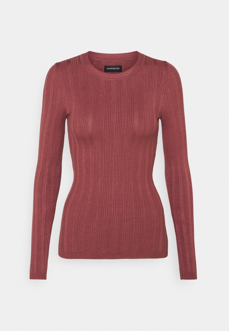 Pull moulant à manches longues en tricot côtelé de couleur rose poussière, avec un col rond et de légères rayures verticales texturées.