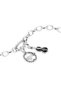 Silbernes Gliederarmband mit runden und Geigenanhängern. Der runde Anhänger zeigt ein stilisiertes "W" mit Perlenakzenten; die Geige ist schwarz mit silbernen Details.