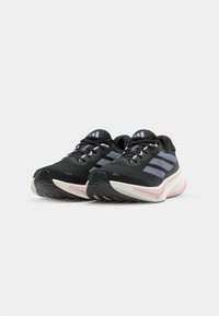 Zwarte sportieve schoenen met roze accenten, voorzien van een ademende mesh bovenkant, een gevoerde zool en drie blauwe strepen aan de zijkant.
