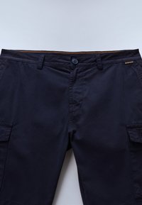 Marineblå cargoshorts med flere lommer, knaplukning og kontrasterende orange syninger langs taljen. Holdbart bomuldsmateriale.