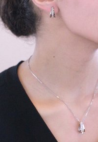Orecchini d'argento con un design angolare unico e piccole pietre preziose trasparenti. Una delicata collana in argento con un pendente abbinato.