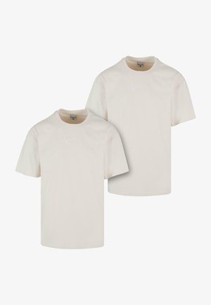 To let beige bomulds t-shirts med korte ærmer og rund hals, med et diskret broderet logo på forsiden.