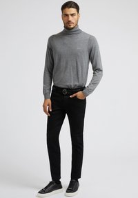 Szürke garbó, slim-fit fekete farmernadrág, fekete sneaker. Egyszerű dizájn, rendezett kivitelezés, finom textúrájú részletekkel.