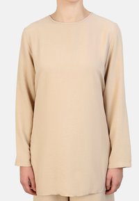 Beige langetermijn top van zacht, gestructureerd stof met een ronde hals, rechte snit en minimale naden.