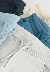 Katoenen hoodies in verschillende tinten blauw, grijs en cream met geribbelde texturen en bijpassende trekkoorden. Meerdere lagen weergegeven.