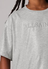 Šedé tričko s krátkým rukávem a měkkým, texturovaným povrchem. Obsahuje vyvýšené logo "ALLSAINTS" v ladícím vlákně pro subtilní akcent.