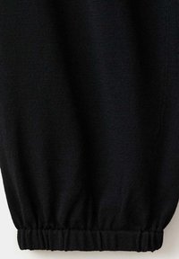 Tissu tricoté noir avec ourlet élastique froncé en bas, créant une apparence légèrement bouffante.