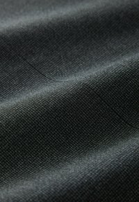 Tissu texturé en gris foncé, présentant un motif de tissage serré. La surface présente des variations subtiles de teinte et une finition lisse.