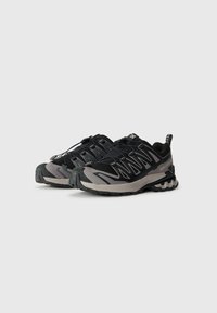 Zwarte en grijze sport schoenen met een gestructureerde bovenkant, voorzien van een veilig vetersysteem, verstevigde neus en robuuste buitenzool voor grip.