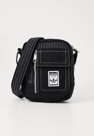 Borsa a tracolla nera con strisce bianche, una tasca anteriore e un'etichetta brandizzata. Presenta una chiusura con zip e una tracolla regolabile. Tessuto resistente.