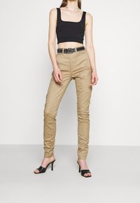 Tan cargo byxor med en insittande form, flera fickor och svart bälte. Matchat med en svart kortärmad topp och svarta klacksandaler.