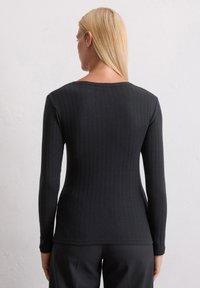 Schwarzes, geripptes Langarmoberteil mit rundem Ausschnitt, figurbetonter Silhouette und strukturiertem Stoff. Einfaches und vielseitiges Design.
