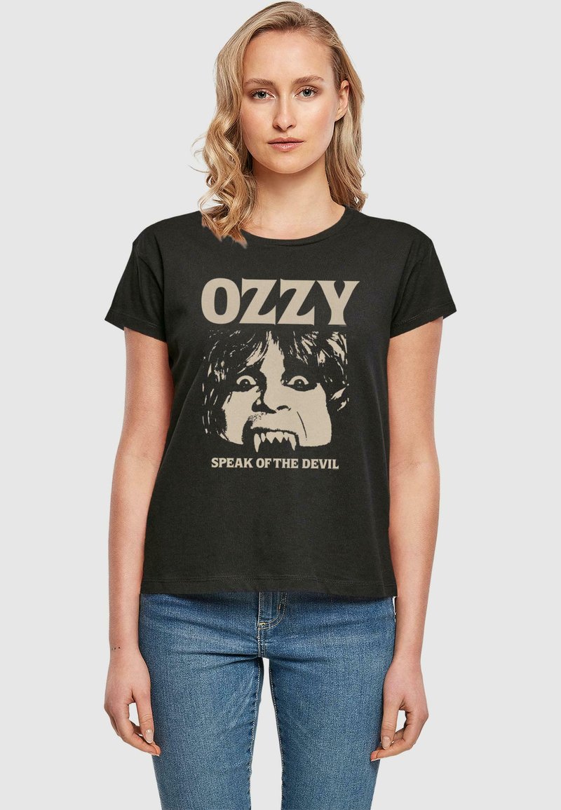 Juodas medvilnės marškinėlis su veido grafika ir iltimis, viršuje tekstas "OZZY" ir apačioje "SPEAK OF THE DEVIL" smėlio spalva.