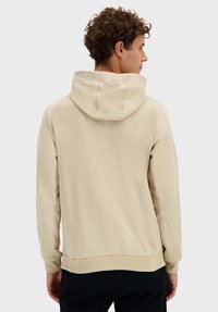 Sudadera con capucha beige, con un bolsillo canguro frontal, puños y dobladillo acanalados, textura suave y un ajuste relajado.