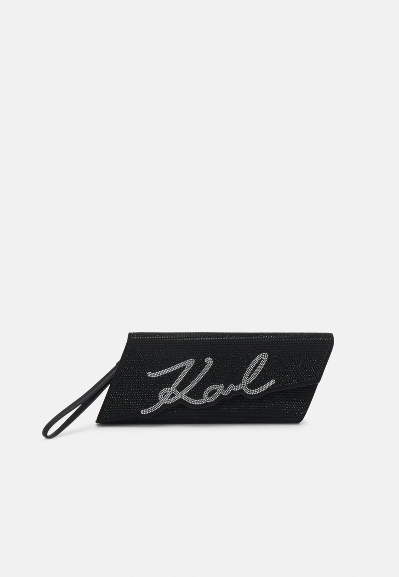 Pochette noire avec une surface texturée, dotée d'un accent en rhinestones argenté représentant une signature. Design slim et bracelet pour une manipulation facile.